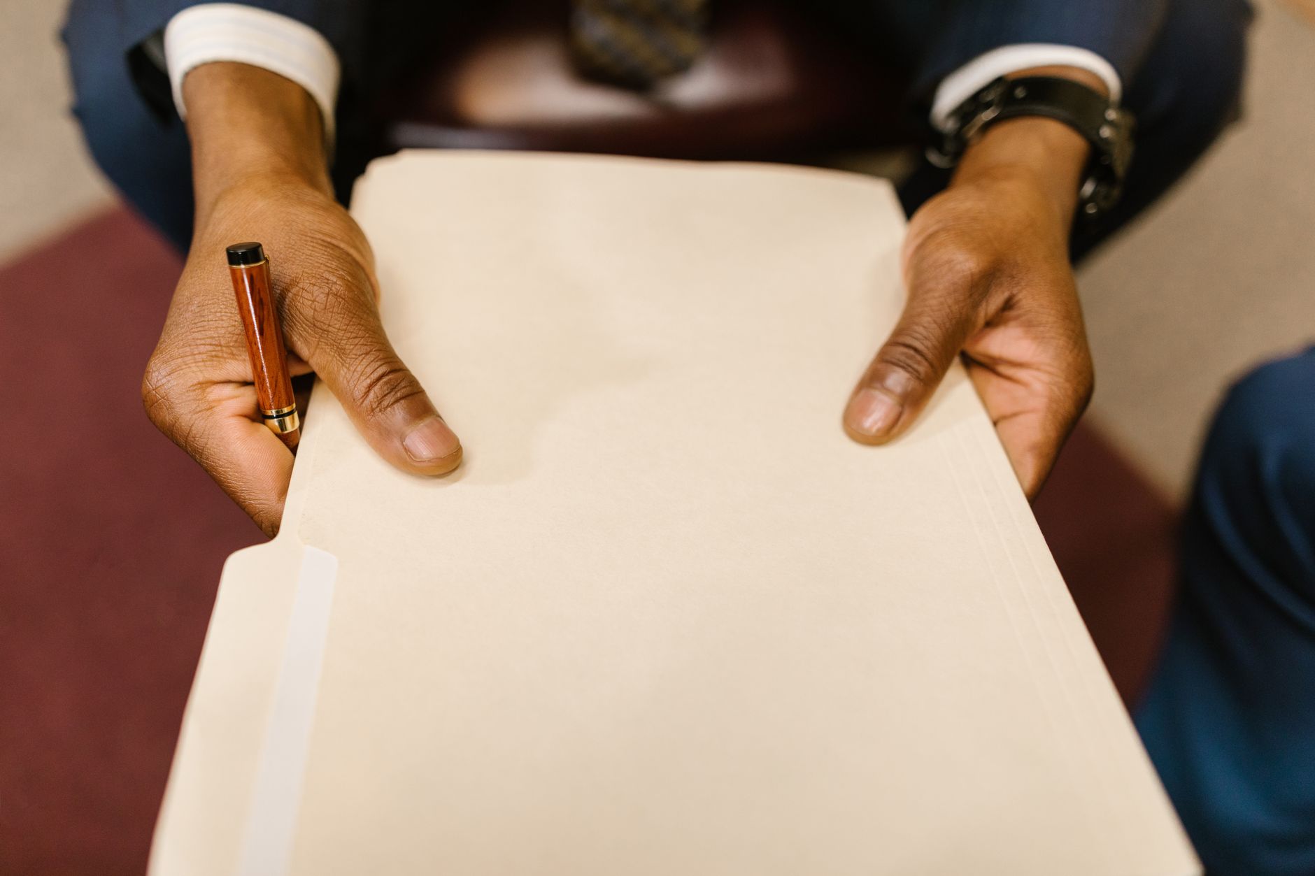 A person in a suit holding a legal folder and pen