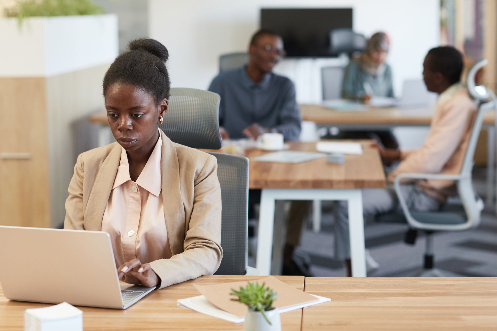 A woman in a blazer working at a laptop